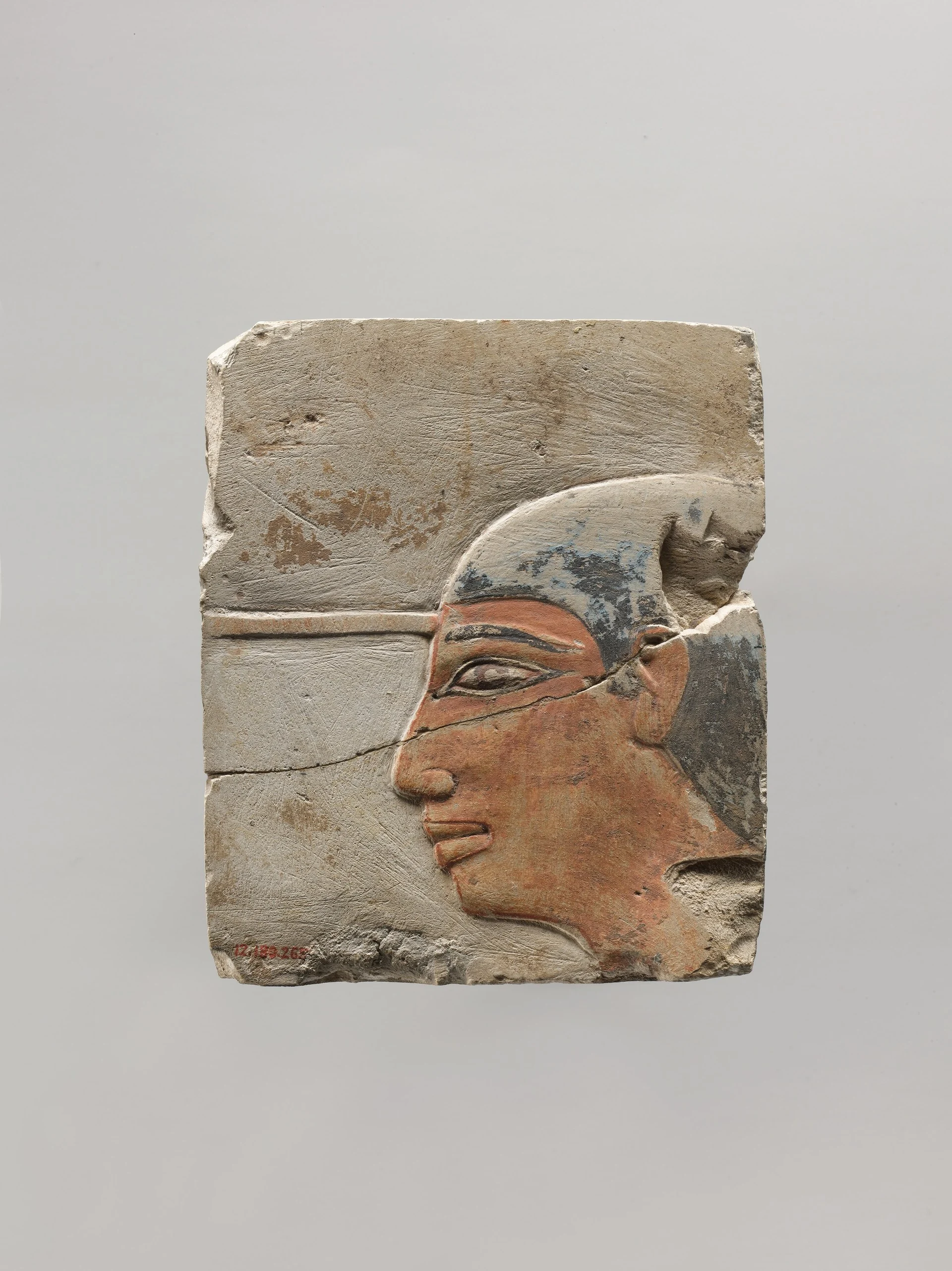 A relief with the head of a scribe: workshop work to order, with deadlines and a budget — and a thing people still stop in front of three thousand years later